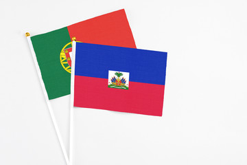 Haiti and Portugal stick flags on white background. High quality fabric, miniature national flag. Peaceful global concept.White floor for copy space.