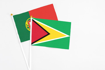 Guyana and Portugal stick flags on white background. High quality fabric, miniature national flag. Peaceful global concept.White floor for copy space.