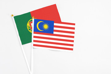 Malaysia and Portugal stick flags on white background. High quality fabric, miniature national flag. Peaceful global concept.White floor for copy space.