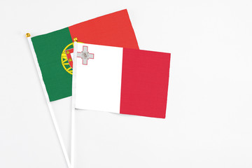 Malta and Portugal stick flags on white background. High quality fabric, miniature national flag. Peaceful global concept.White floor for copy space.