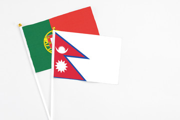 Nepal and Portugal stick flags on white background. High quality fabric, miniature national flag. Peaceful global concept.White floor for copy space.