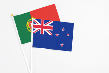 Fototapeta premium New Zealand and Portugal stick flags on white background. High quality fabric, miniature national flag. Peaceful global concept.White floor for copy space.