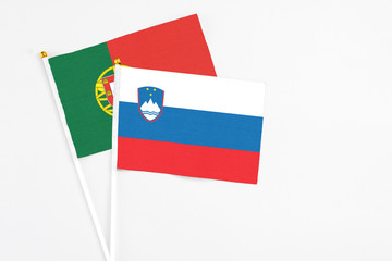 Slovenia and Portugal stick flags on white background. High quality fabric, miniature national flag. Peaceful global concept.White floor for copy space.