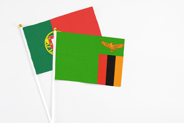 Zambia and Portugal stick flags on white background. High quality fabric, miniature national flag. Peaceful global concept.White floor for copy space.