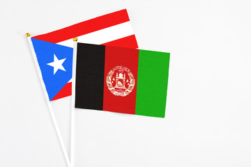 Afghanistan and Puerto Rico stick flags on white background. High quality fabric, miniature national flag. Peaceful global concept.White floor for copy space.