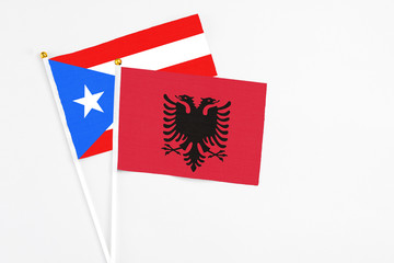 Fototapeta premium Albania and Puerto Rico stick flags on white background. High quality fabric, miniature national flag. Peaceful global concept.White floor for copy space.