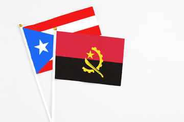 Angola and Puerto Rico stick flags on white background. High quality fabric, miniature national flag. Peaceful global concept.White floor for copy space.