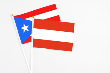 Austria and Puerto Rico stick flags on white background. High quality fabric, miniature national flag. Peaceful global concept.White floor for copy space.
