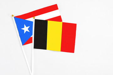 Belgium and Puerto Rico stick flags on white background. High quality fabric, miniature national flag. Peaceful global concept.White floor for copy space.