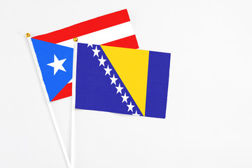 Bosnia Herzegovina and Puerto Rico stick flags on white background. High quality fabric, miniature national flag. Peaceful global concept.White floor for copy space.