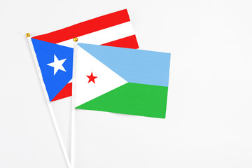 Djibouti and Puerto Rico stick flags on white background. High quality fabric, miniature national flag. Peaceful global concept.White floor for copy space.