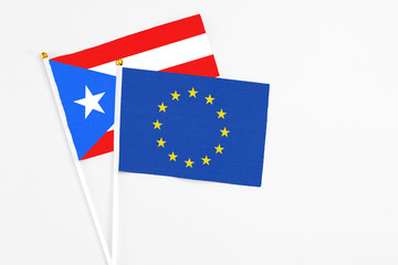 European Union and Puerto Rico stick flags on white background. High quality fabric, miniature national flag. Peaceful global concept.White floor for copy space.