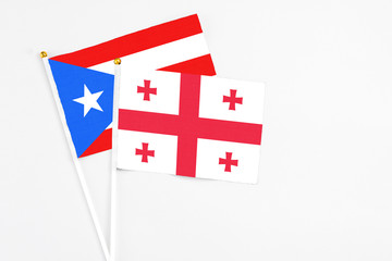 Georgia and Puerto Rico stick flags on white background. High quality fabric, miniature national flag. Peaceful global concept.White floor for copy space.