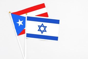 Fototapeta premium Israel and Puerto Rico stick flags on white background. High quality fabric, miniature national flag. Peaceful global concept.White floor for copy space.