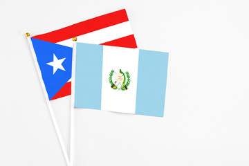 Fototapeta na wymiar Guatemala and Puerto Rico stick flags on white background. High quality fabric, miniature national flag. Peaceful global concept.White floor for copy space.