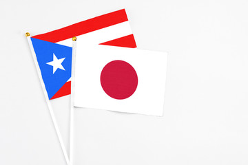 Japan and Puerto Rico stick flags on white background. High quality fabric, miniature national flag. Peaceful global concept.White floor for copy space.