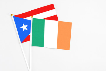 Fototapeta na wymiar Ireland and Puerto Rico stick flags on white background. High quality fabric, miniature national flag. Peaceful global concept.White floor for copy space.