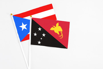 Papua New Guinea and Puerto Rico stick flags on white background. High quality fabric, miniature national flag. Peaceful global concept.White floor for copy space.