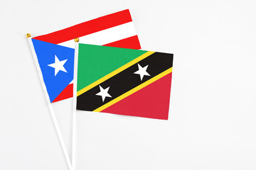 Saint Kitts And Nevis and Puerto Rico stick flags on white background. High quality fabric, miniature national flag. Peaceful global concept.White floor for copy space.