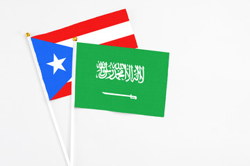Saudi Arabia and Puerto Rico stick flags on white background. High quality fabric, miniature national flag. Peaceful global concept.White floor for copy space.