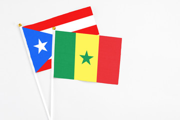 Senegal and Puerto Rico stick flags on white background. High quality fabric, miniature national flag. Peaceful global concept.White floor for copy space.