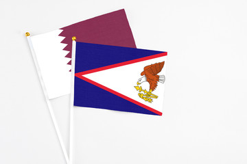 American Samoa and Qatar stick flags on white background. High quality fabric, miniature national flag. Peaceful global concept.White floor for copy space.