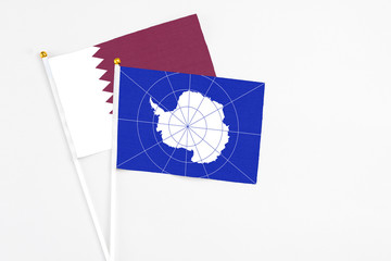 Antarctica and Qatar stick flags on white background. High quality fabric, miniature national flag. Peaceful global concept.White floor for copy space.