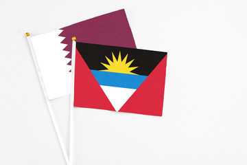Obraz premium Antigua and Barbuda and Qatar stick flags on white background. High quality fabric, miniature national flag. Peaceful global concept.White floor for copy space.