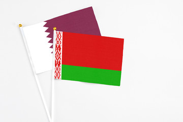 Belarus and Qatar stick flags on white background. High quality fabric, miniature national flag. Peaceful global concept.White floor for copy space.