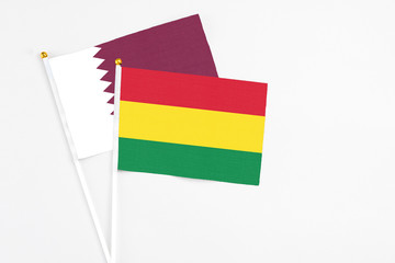 Bolivia and Qatar stick flags on white background. High quality fabric, miniature national flag. Peaceful global concept.White floor for copy space.