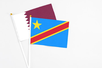 Congo and Qatar stick flags on white background. High quality fabric, miniature national flag. Peaceful global concept.White floor for copy space.