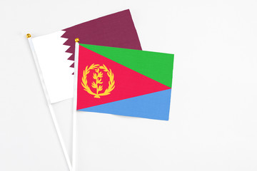 Eritrea and Qatar stick flags on white background. High quality fabric, miniature national flag. Peaceful global concept.White floor for copy space.