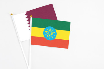 Ethiopia and Qatar stick flags on white background. High quality fabric, miniature national flag. Peaceful global concept.White floor for copy space.