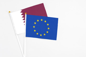 European Union and Qatar stick flags on white background. High quality fabric, miniature national flag. Peaceful global concept.White floor for copy space.