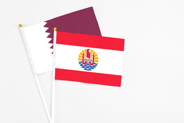 French Polynesia and Qatar stick flags on white background. High quality fabric, miniature national flag. Peaceful global concept.White floor for copy space.