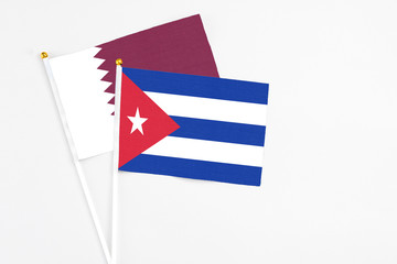 Cuba and Qatar stick flags on white background. High quality fabric, miniature national flag. Peaceful global concept.White floor for copy space.