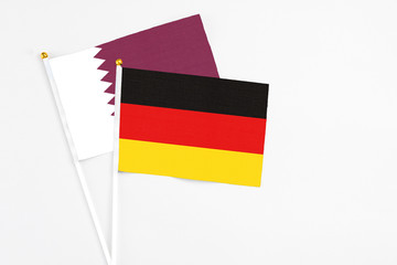 Germany and Qatar stick flags on white background. High quality fabric, miniature national flag. Peaceful global concept.White floor for copy space.
