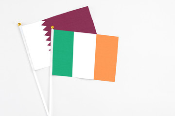 Ireland and Qatar stick flags on white background. High quality fabric, miniature national flag. Peaceful global concept.White floor for copy space.