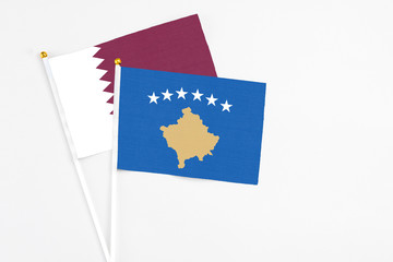 Kosovo and Qatar stick flags on white background. High quality fabric, miniature national flag. Peaceful global concept.White floor for copy space.