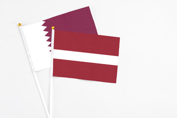 Latvia and Qatar stick flags on white background. High quality fabric, miniature national flag. Peaceful global concept.White floor for copy space.