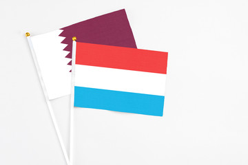 Luxembourg and Qatar stick flags on white background. High quality fabric, miniature national flag. Peaceful global concept.White floor for copy space.