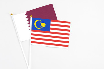 Malaysia and Qatar stick flags on white background. High quality fabric, miniature national flag. Peaceful global concept.White floor for copy space.