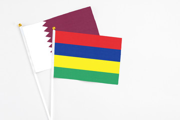 Mauritius and Qatar stick flags on white background. High quality fabric, miniature national flag. Peaceful global concept.White floor for copy space.