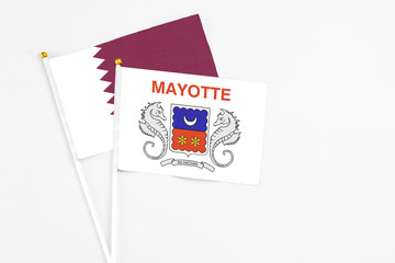 Mayotte and Qatar stick flags on white background. High quality fabric, miniature national flag. Peaceful global concept.White floor for copy space.