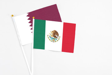 Mexico and Qatar stick flags on white background. High quality fabric, miniature national flag. Peaceful global concept.White floor for copy space.