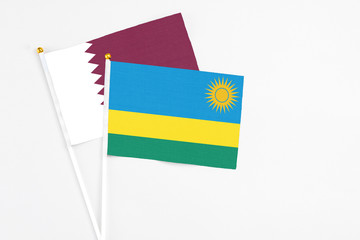 Rwanda and Qatar stick flags on white background. High quality fabric, miniature national flag. Peaceful global concept.White floor for copy space.