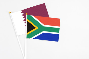 South Africa and Qatar stick flags on white background. High quality fabric, miniature national flag. Peaceful global concept.White floor for copy space.