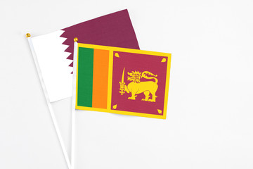 Sri Lanka and Qatar stick flags on white background. High quality fabric, miniature national flag. Peaceful global concept.White floor for copy space.