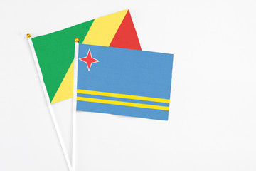 Aruba and Republic Of The Congo stick flags on white background. High quality fabric, miniature national flag. Peaceful global concept.White floor for copy space.
