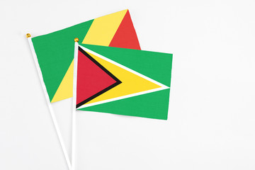 Obraz premium Guyana and Republic Of The Congo stick flags on white background. High quality fabric, miniature national flag. Peaceful global concept.White floor for copy space.
